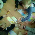 Uczniowie rozwiązują zadania z kolorowych kart z zagadkami