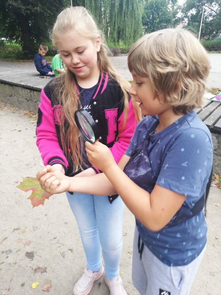 Uczniowie obserwują liść za pomocą lupy